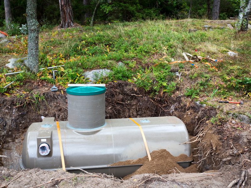 A new septic tank set into an excavated pit beside a wooded lot