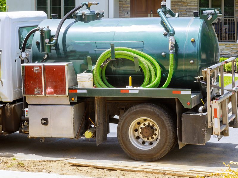 A vacuum service truck parked in a residential driveway
